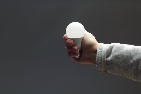 Energy saving daylight bulb, in the hand of an adult; bulb prepared to be installed and connected to electricity; It gives light and little heat.の写真素材