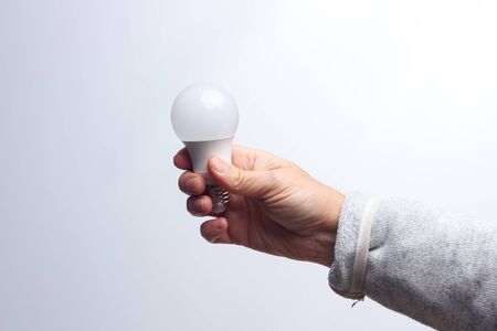 Energy saving daylight bulb, in the hand of an adult; bulb prepared to be installed and connected to electricity; It gives light and little heat.の写真素材
