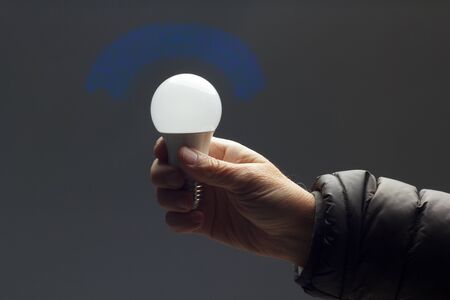 Energy saving daylight bulb, in the hand of an adult; bulb prepared to be installed and connected to electricity; It gives light and little heat.の写真素材