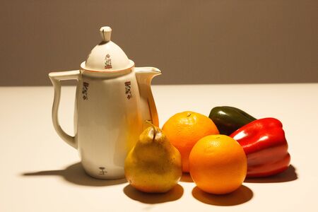 Vintage coffee maker with orange fruits, banana and red and green pepper. Classic minimalist still life with light, light and shadow proofs.の写真素材