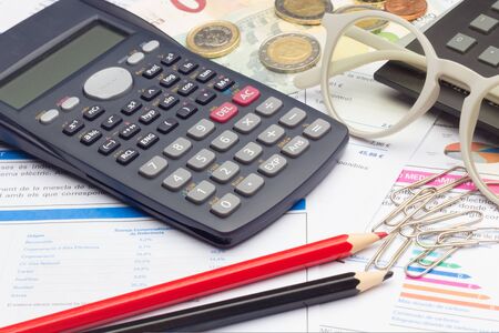 Papers, glasses and calculator to make calculations of the invoices we receive, to make graphs and statistics of our expenses or benefits. scientific calculator used by science studentsの写真素材