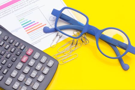 Papers, glasses and calculator to make calculations of the invoices we receive, to make graphs and statistics of our expenses or benefits. scientific calculator used by science studentsの写真素材