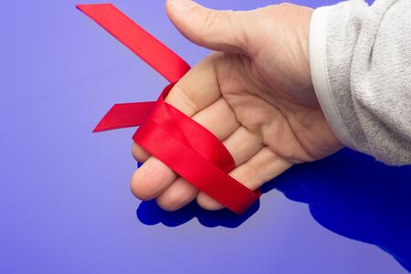 Red cloth ribbon to make bows and decorate gift boxes above the wrapping paper, in the hand of an...
