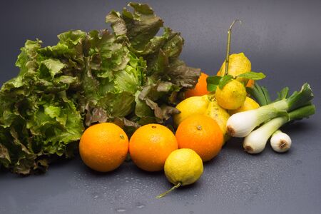 Fruits, oranges and lemons and vegetables and winter, spring onion and green lettuce, citrus, all organic, freshly picked from the garden.の写真素材