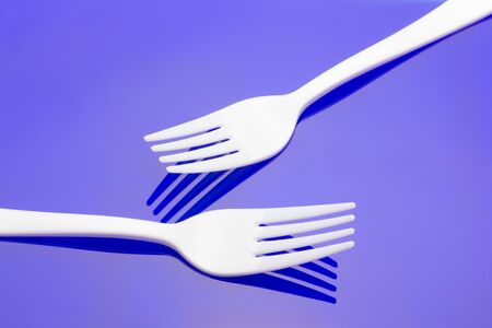 Plastic fork on colored background; fork for casual food, covered in white to prick and make casual food, ideal for family meals, parties, catering.の写真素材