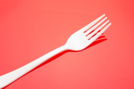 Plastic fork on colored background; fork for casual food, covered in white to prick and make casual food, ideal for family meals, parties, catering.の写真素材