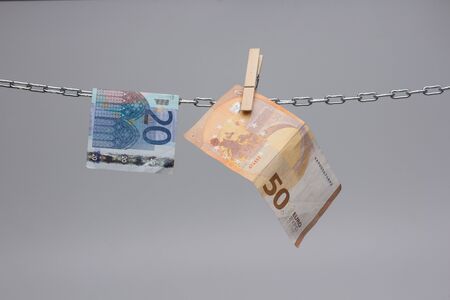 Euro banknotes, currency of the economic community of Europe, hung on a chain, 50, 20, 10 and 5 euro bills. Money in paper money hung and held by tweezers in a chain.の写真素材
