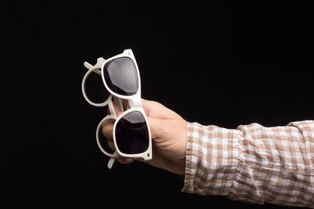 Visual health in the glasses, give away glasses for vision correction, colored designer glasses on a black background. Colored lenses in the hand of an adult person. Correction in the lenses of the glasses.の写真素材
