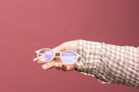 Designer glasses and lenses in the hand of an adult, glasses with corrected glasses for correct vision, colored glasses with a modern design.の写真素材