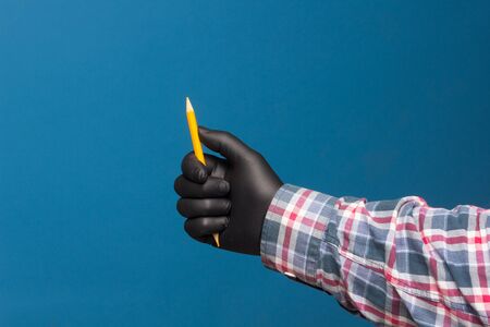 Color pencil with black hygienic protection glove on blue background. Pencil for drawing. pencil with sharp pointの写真素材