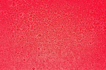 Small and irregular drops of water on a shiny green surface.の写真素材