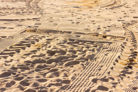 portion of beach sand in summer with the footprints of people who have stepped on it