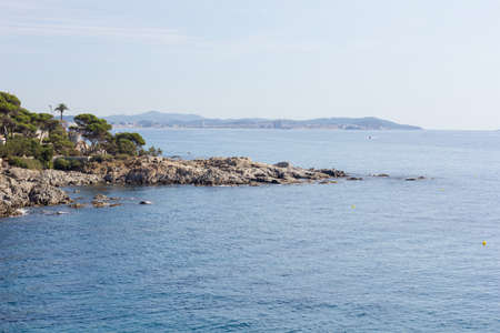 Costa Brava, Baix Ampurdan, Catalonia, Spain; where the mountain reaches the sea, the pines touch the Mediterranean water, blue water, blue sky.の写真素材