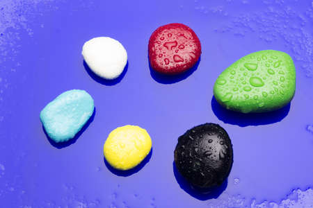 Color stones on a green background; various colors, yellow, black, white, maroon, blue, basic...