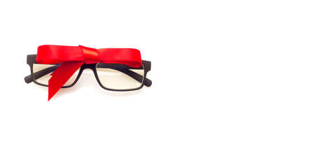 Glasses with graduated glasses and black frame, classic plastic on white background and red gift ribbonの写真素材