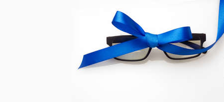Glasses with graduated glasses and black frame, classic plastic on white background and red gift ribbonの写真素材