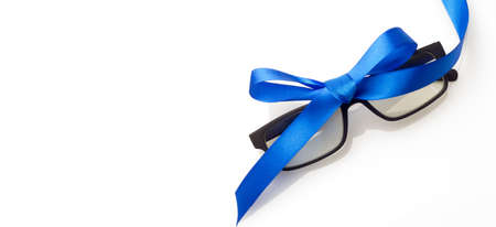 Glasses with graduated glasses and black frame, classic plastic on white background and red gift ribbonの写真素材