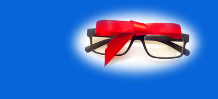 Glasses with graduated glasses and black frame, classic plastic on white background and red gift ribbonの写真素材