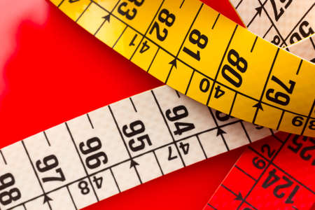 Yellow tape measure for measuring perimeters of objects; tailor's and dressmaker's tape for taking body measurements.の写真素材