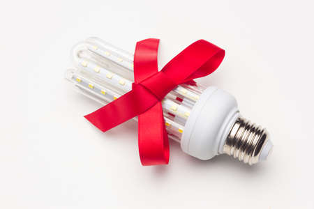 Energy-saving light bulb with a red ribbon; saving is a gift in addition to preventing global...