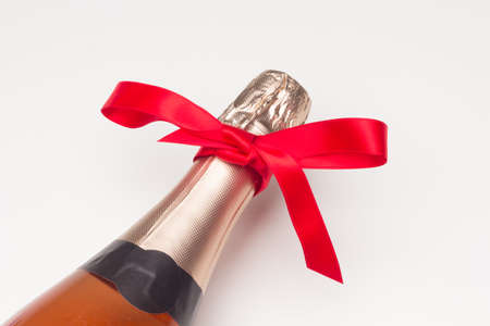 Campagne bottle with a red gift ribbon on a white background. Elegant bottle with a bow to be given as a gift.の写真素材