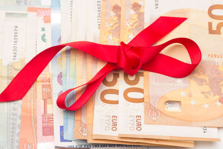 Money as a gift; giving money as a gift at anniversary or Christmas parties; money with a red ribbon; when we lack ideas, money is given as a gift.の写真素材