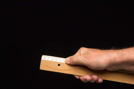 Wooden ruler, classic for taking measurements and making technical drawings, on a black background....