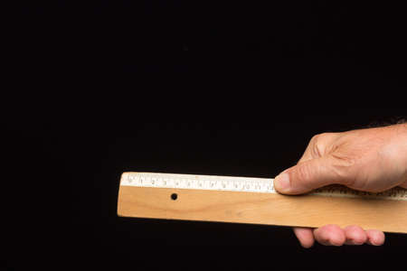 Wooden ruler, classic for taking measurements and making technical drawings, on a black background....