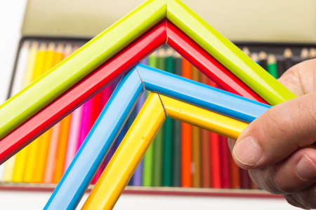 Hand, fingers and range of colors; colored pencils, full range; colored angles held by adult hand
