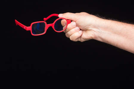 Modern glasses, prescription, on a black background, in the hand of an adult person