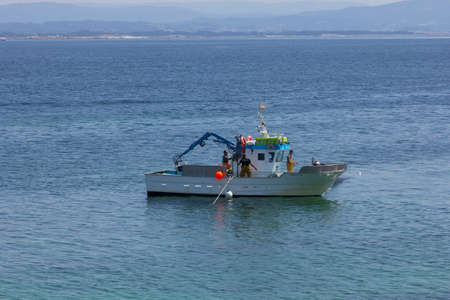 Fishing boat, collecting nets full of fish. fishing near the coast.の写真素材