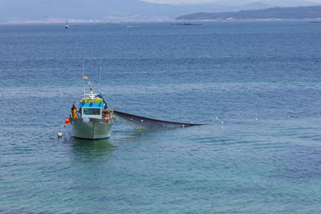 Fishing boat, collecting nets full of fish. fishing near the coast.の写真素材