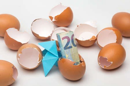 Broken eggs and paper bow ties on a plain background