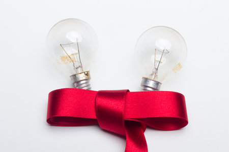 incandescent bulbs and red ribbon on a white backgroundの写真素材