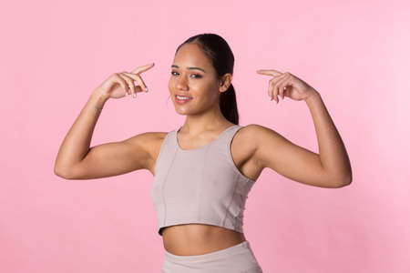 Young girl doing gymnastic exercises and stretching before starting sport activity on a pink background.の写真素材