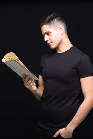 Young boy with glasses reading a book on a black backgroundの写真素材