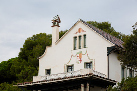 Traditional Spanish villa showcasing white walls, decorative chimney, and a balcony with intricate details, set against a backdrop of treesの写真素材
