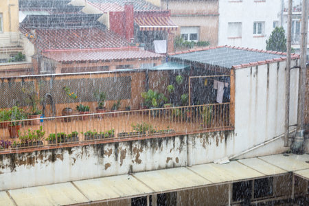 Laundry drying on a clothesline on a balcony is getting wet during a sudden rain shower