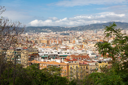 Three industrial chimneys rising above a modern building in Barcelona, offering a panoramic...