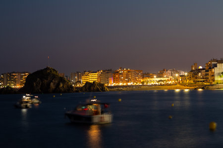 Tourists and locals are enjoying a summer night on the beach, watching a festival with amusement rides and live musicの写真素材