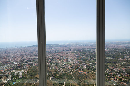 Aerial view of Barcelona city with its urban sprawl extending towards the Mediterranean sea, featuring cargo ships dotting the horizonの写真素材