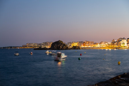Tourists and locals are enjoying a summer night on the beach, watching a festival with amusement rides and live musicの写真素材