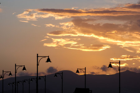 Street lamps create silhouettes against a beautiful sunset sky filled with colorful clouds