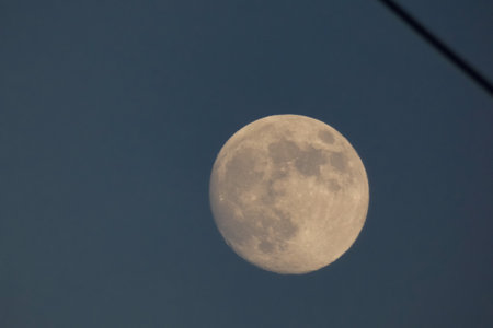 Waxing crescent moon with visible craters in the daytime sky