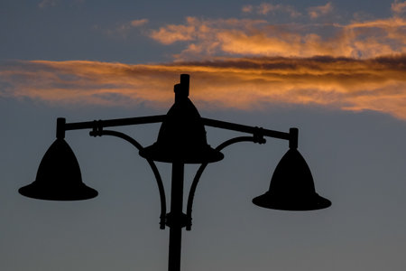 Street lamps create silhouettes against a beautiful sunset sky filled with colorful clouds