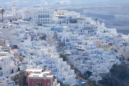 Traditional whitewashed church and houses perched on a cliff overlooking the Aegean Sea in Santorini, Greece, create a picturesque sceneの写真素材