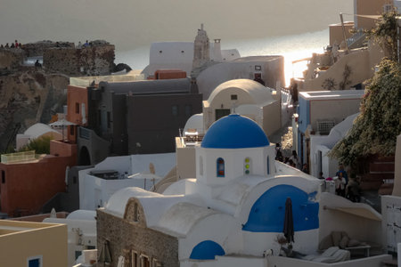 Picturesque white church with blue dome overlooking the Aegean sea with sailboats on a sunny day in Santorini, Greeceの写真素材