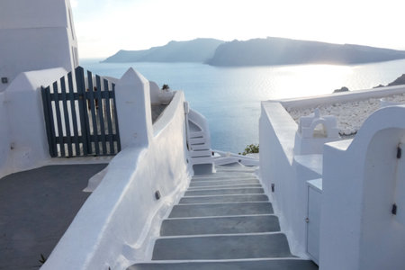 Small plants growing in blue painted flowerpots decorating steps of a white wall