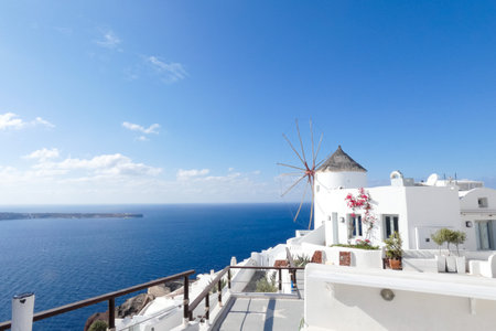 Picturesque whitewashed windmill standing tall against a vibrant blue sky, showcasing traditional...