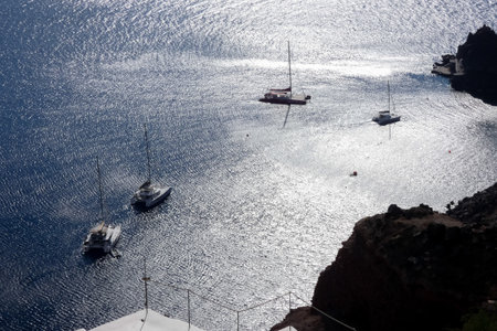 White catamaran sailing on calm ocean water reflecting golden sunset lightの写真素材
